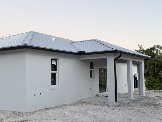 Black gutter wrapping a white house with a metal roof