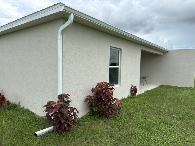 White downspout extending away from a cream home