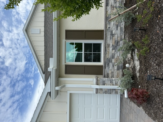 White gutter and downspout beside a stone-clad front entry