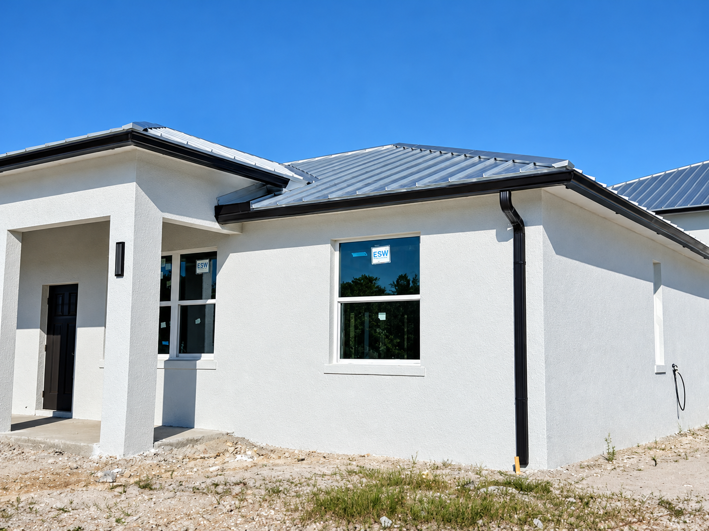 Black gutter installation on a white Southwest Florida home with a metal roof